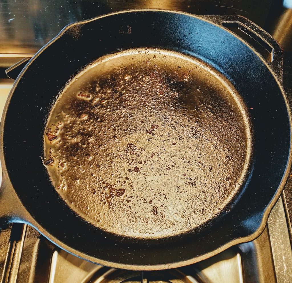 Picture of a cast iron pan with stuck on meat before cleaning.