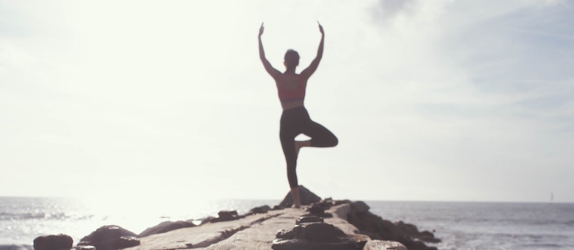 Lady doing a yoga post in background on pier