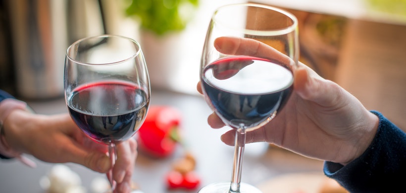 Two people toasting with red wine