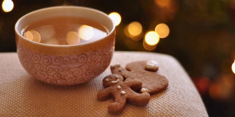 Cider cup next to gingerbread cookies with lights bokeh in back