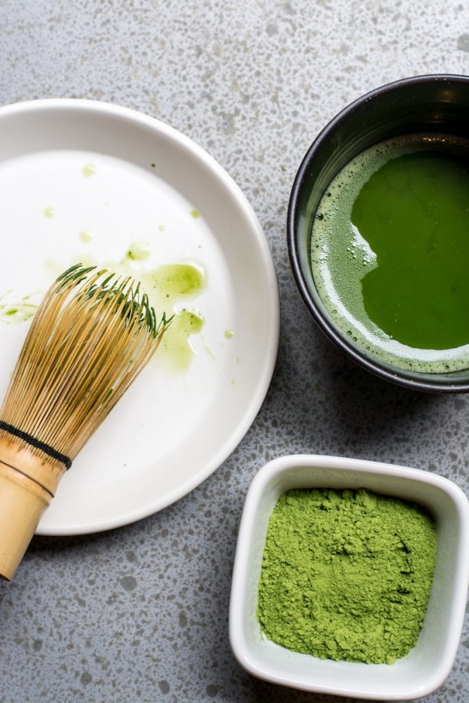 Matcha in bowl next to tea cup with green tea