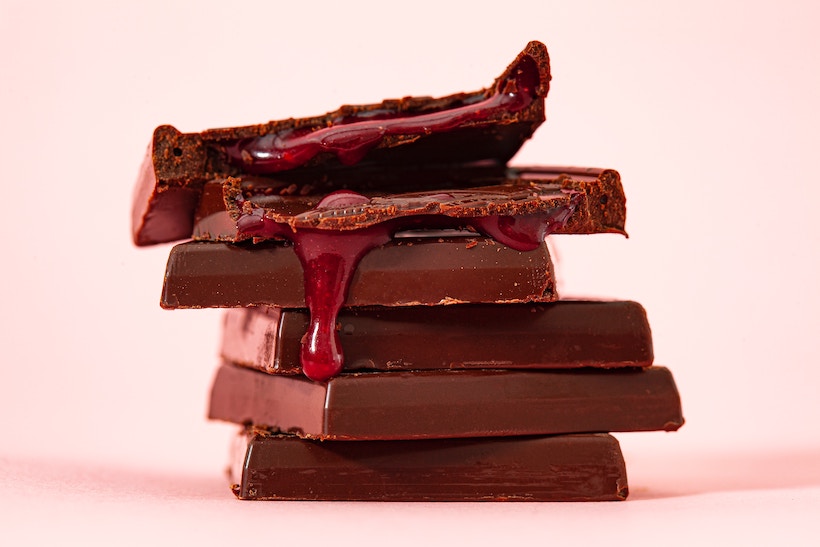 Chocolate squares in a stack with red filling spilling down the sides