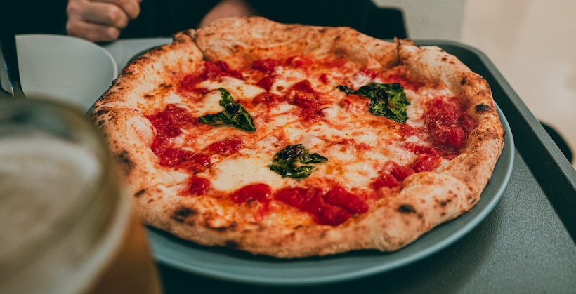 Deep-dish pizza on a plate with spinach on top