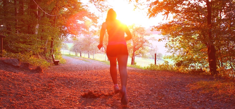 Runner from the back with sun streaming at sunset