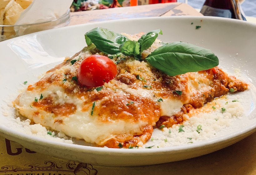 Lasagna on a ceramic plate with tomato and basil