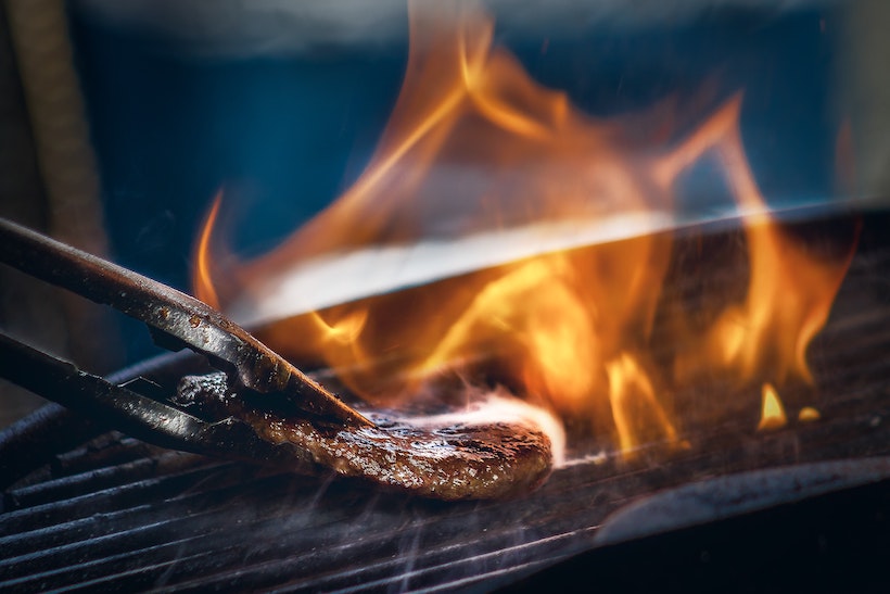 Burger on a cast iron grill with flame