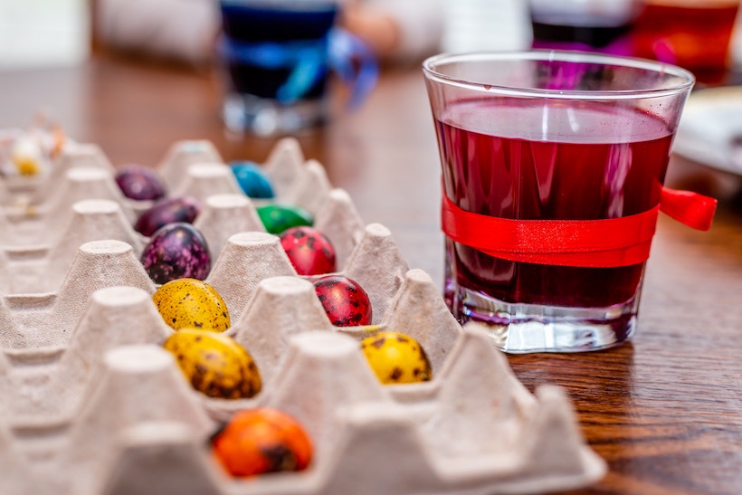 Easter eggs in a tray drying next to red dye water