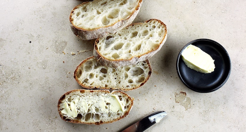 4 slices of bread with butter and a butter knife