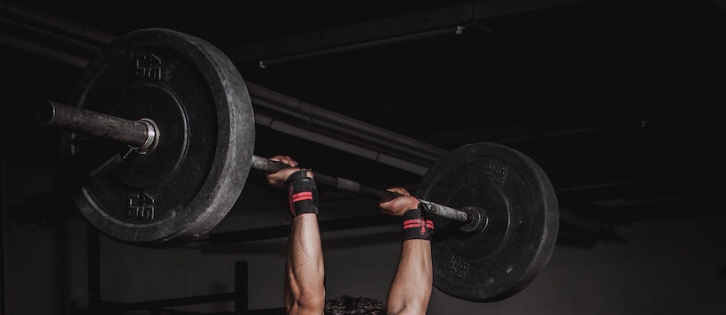 Man lifts a heavy bar with weights over his head