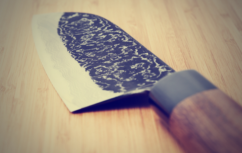 Japanese damascus carbon steel knife on wooden plank, close-up, toned picture