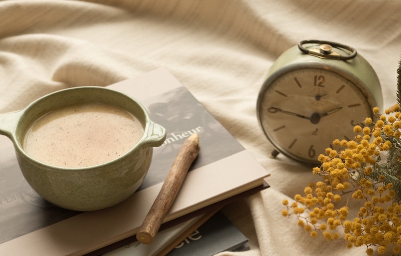 Chai tea on a book next to an alarm clock