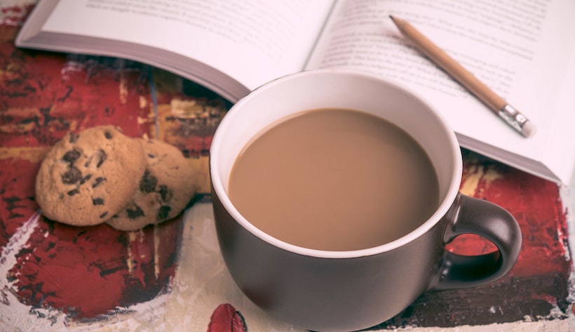 Cookies, coffee with milk, and a pencil on a book