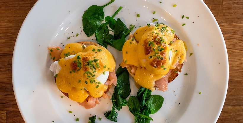 Runny egg with spinach and ham on round bread or bagel