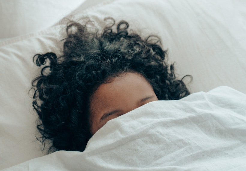 A woman naps under a blanket