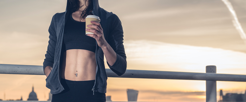 An athletic young woman with toned abs and coffee cup in hand