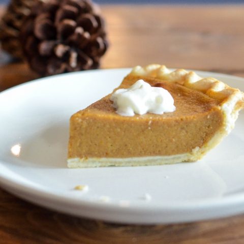 Pumpkin pie slice in front of pinecones