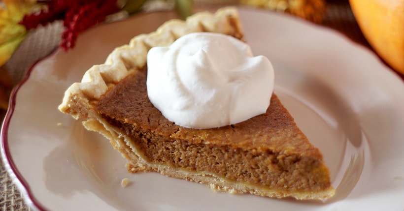 Close up shot of a slice of pumpkin pie on a ceramic plate