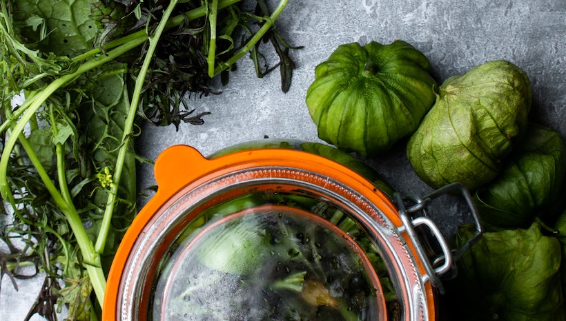 Tomatillos and greens near a pot