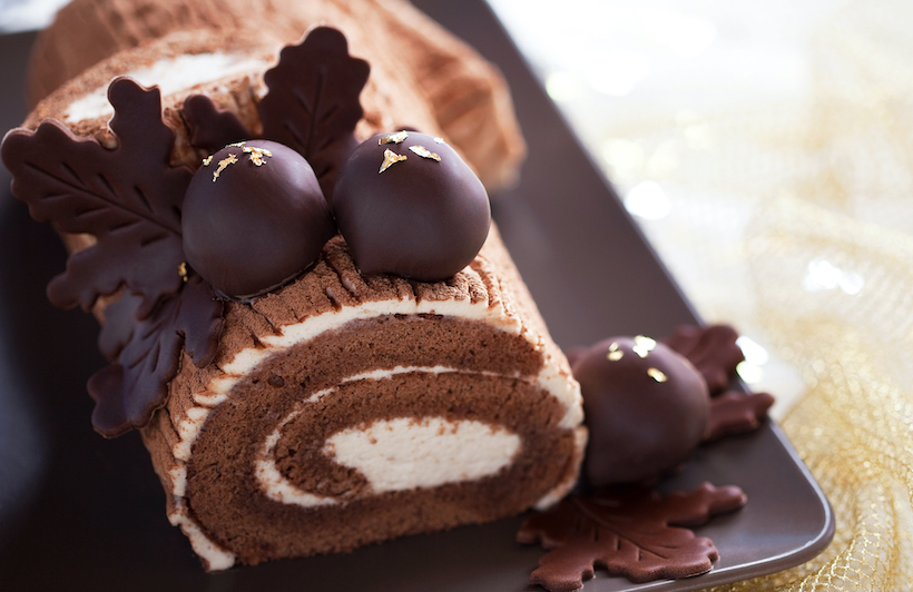 Traditional Christmas Yule Log cake decorated with chocolate chestnuts, selective focus