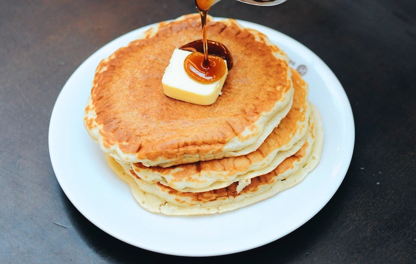 Pancakes on a plate with butter on top and poured syrup